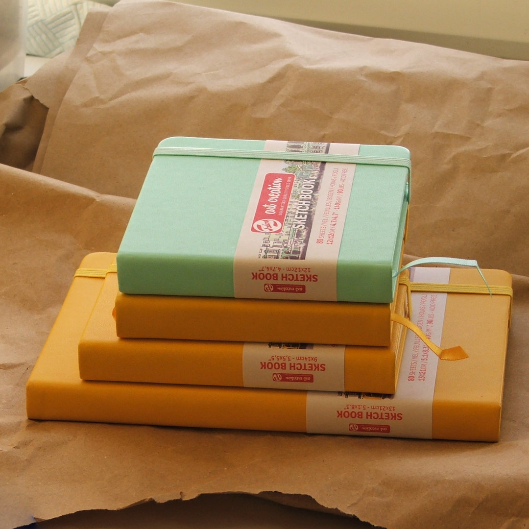 Pile of yellow and green sketchbooks on a crumpled paper background