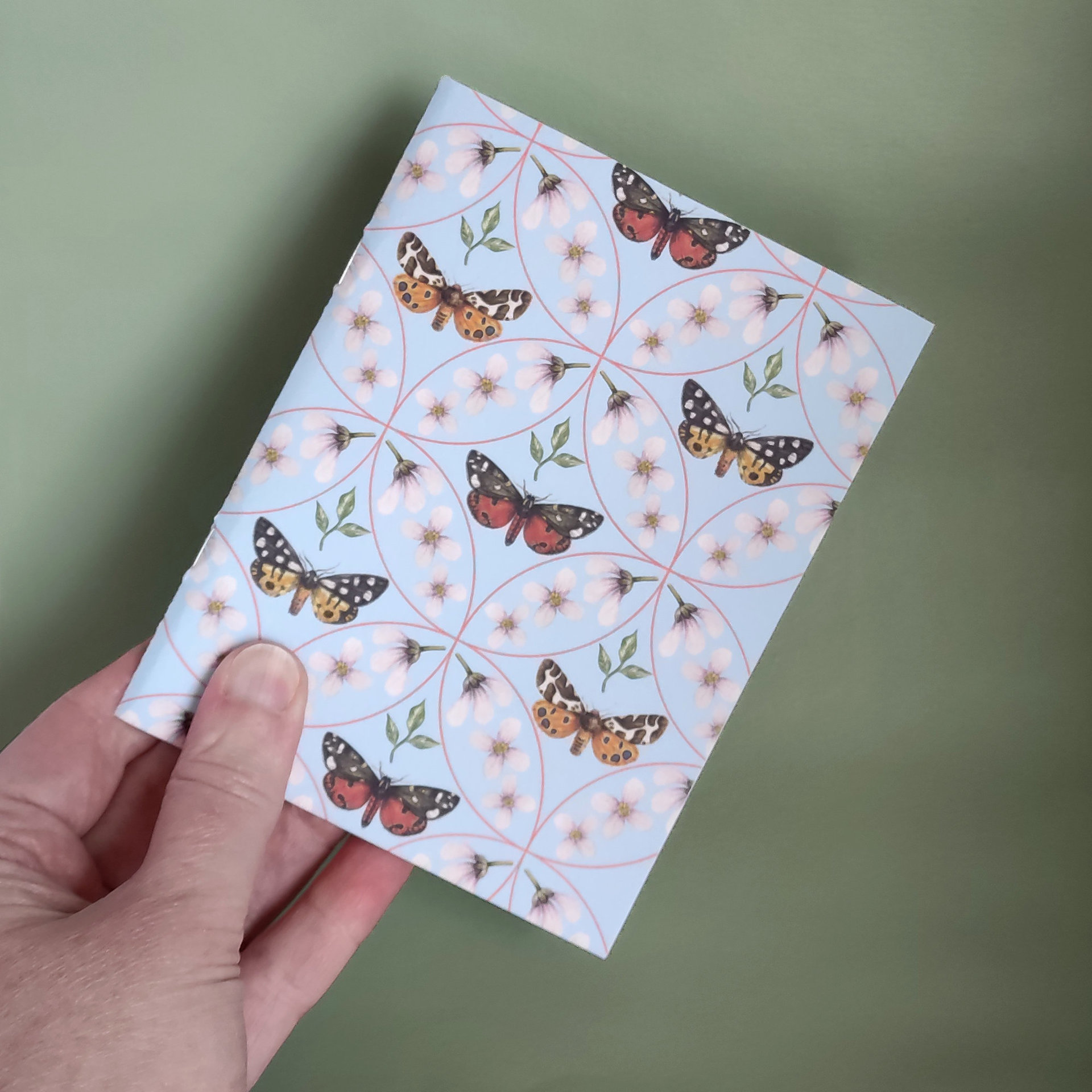 Moth notebook held in a hand to show size