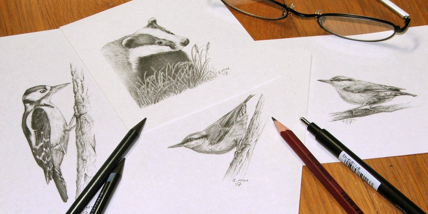 Selection of pencil art on a desk with pencils, eraser and glasses