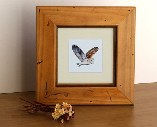 framed barn own painting on tabletop with dried flowers